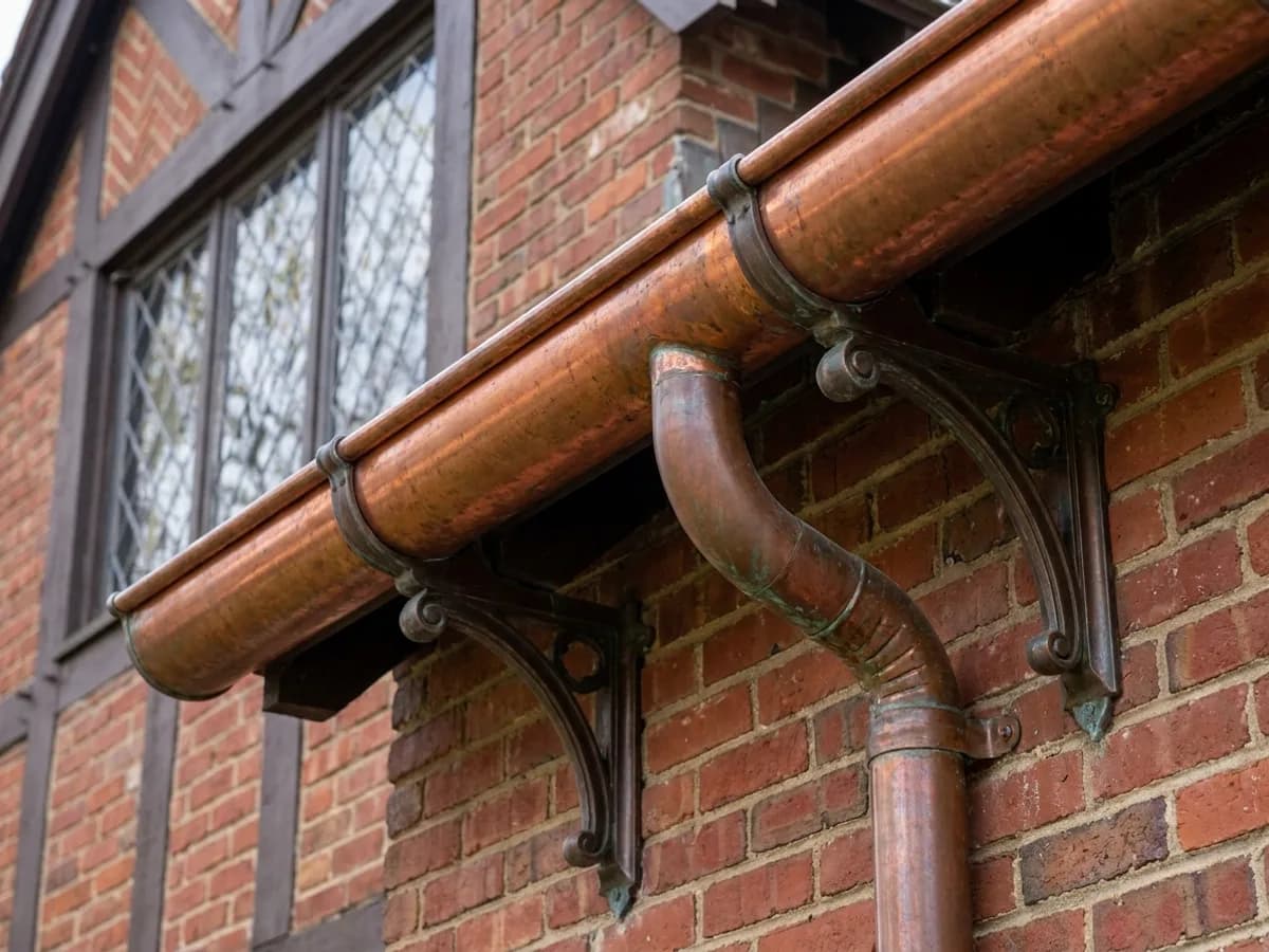Half-round copper gutter on exposed brackets with a round copper downspout