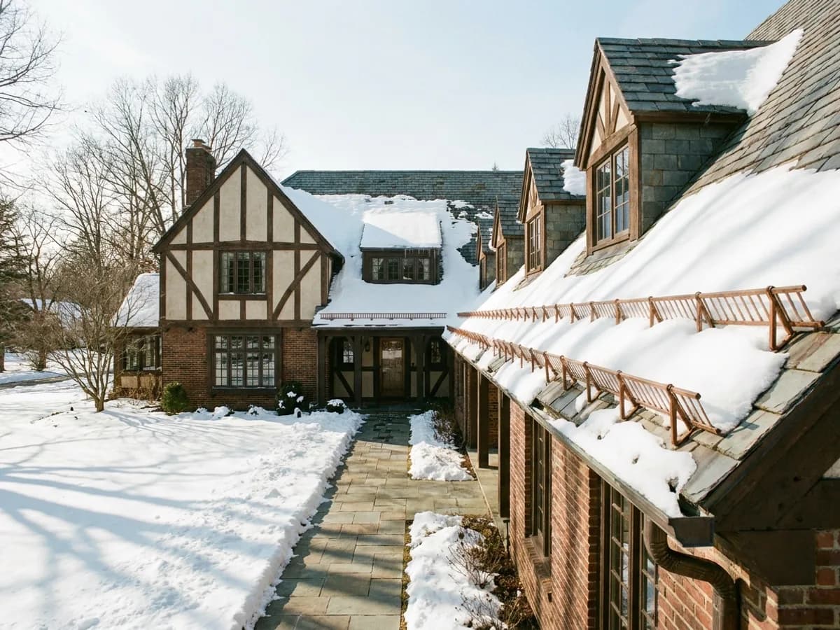 Rows of copper snow guards above the entry and gutters of a slate-roofed Tudor home