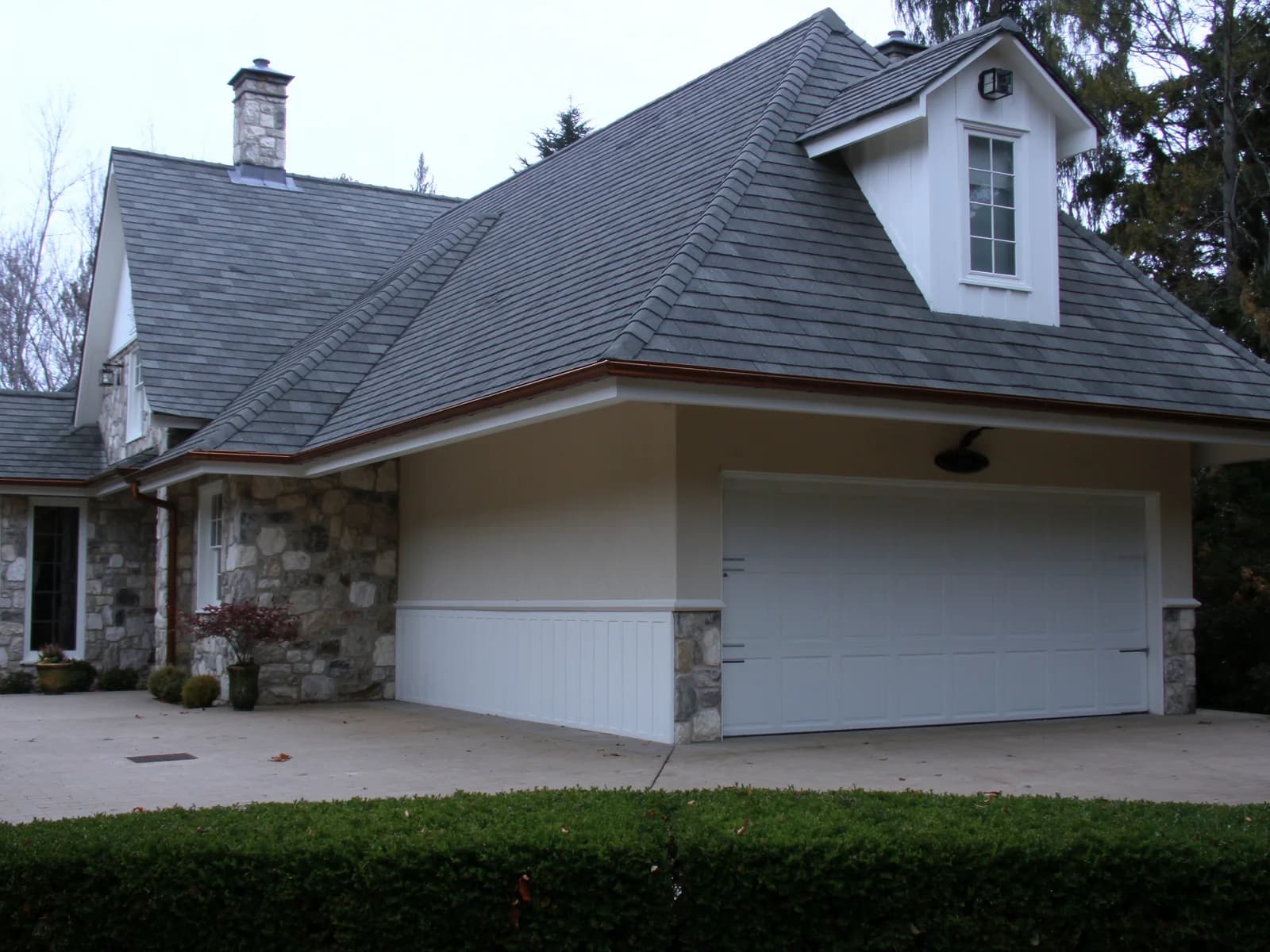 Hipped slate roof over a garage wing, three planes meeting at the hips