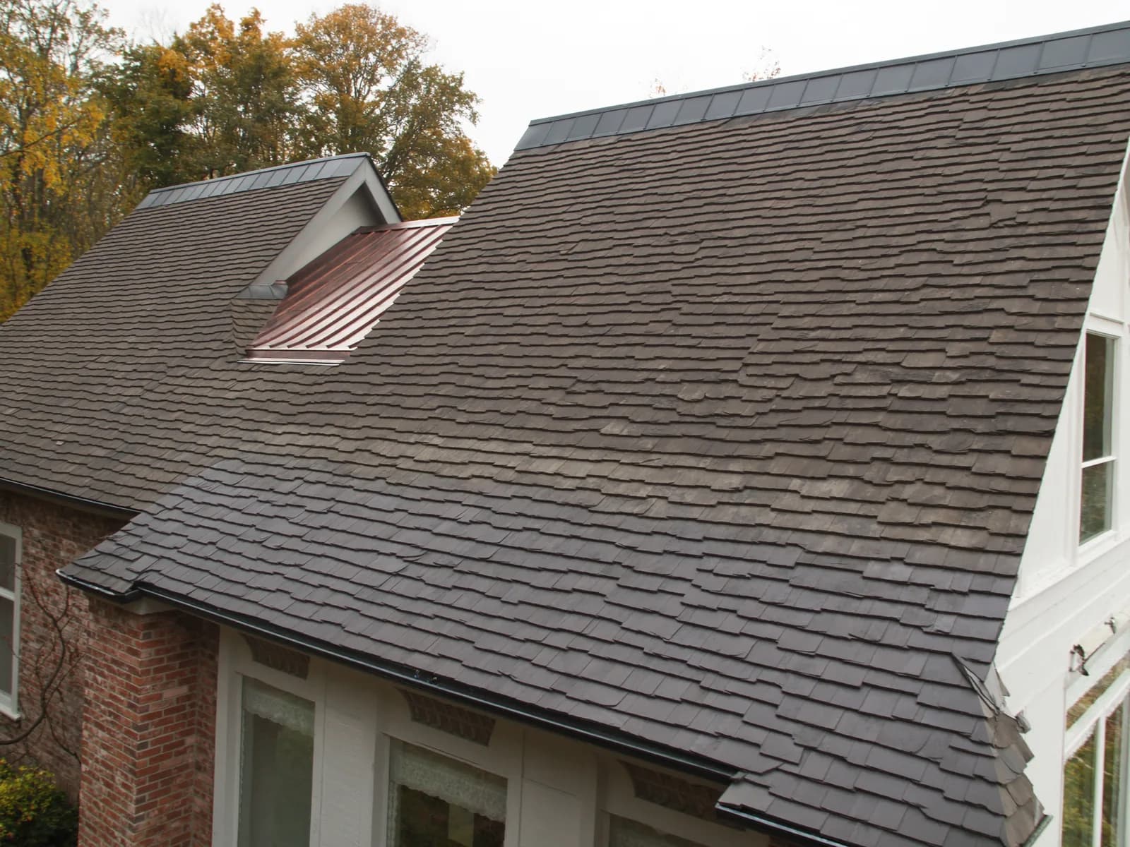 Heavy laminated designer asphalt shingles in a weathered-wood blend, with a copper dormer roof and dark ridge cap