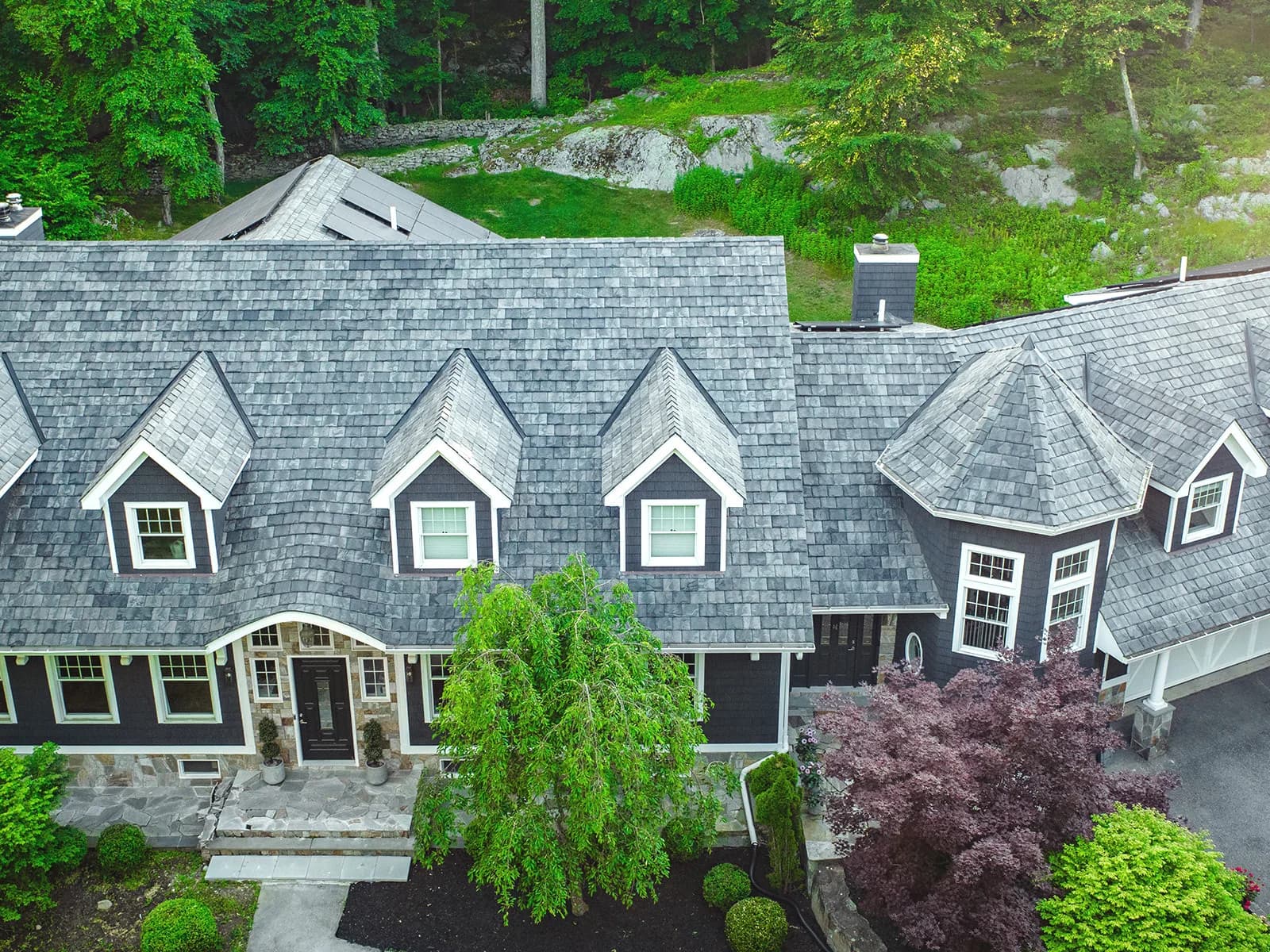 Composite slate roof in multi-width courses over a dormered elevation, in a weathered grey-green blend